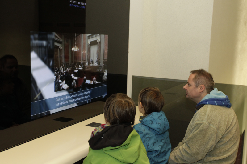 Besucherinnen und Besucher besichtigendie Medeienstationen im BesucherInnenzentrum