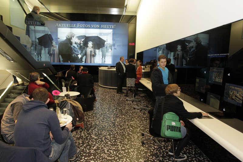 Besucherinnen und Besucher besichtigendie Medeienstationen im BesucherInnenzentrum