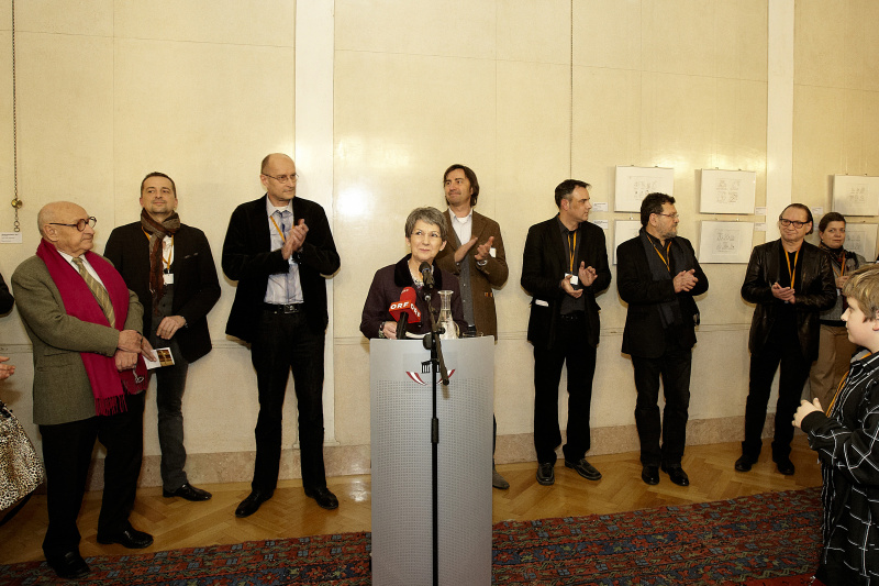 Nationalratspräsidentin Barbara Prammer begrüßt die Gäste der Veranstaltung, im Hintergrund die ausstellenden Kariktaturisten