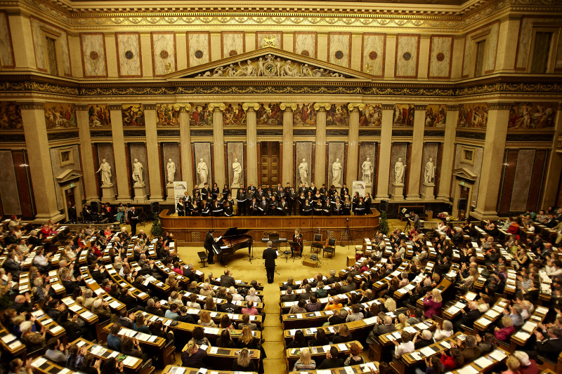 Blick in Richtung VeranstaltungsteilnehmerInnen mit dem Chor auf der Regierungsbank