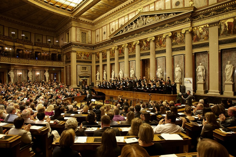Blick in Richtung VeranstaltungsteilnehmerInnen mit dem Chor auf der Regierungsbank