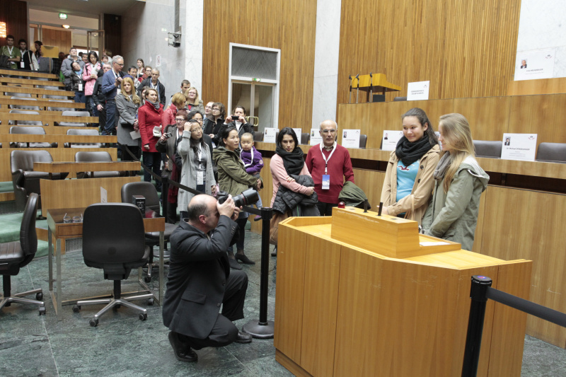 Besucherinnen und Besucher lassen sich am Rednerpult des Nationalrates fotografieren