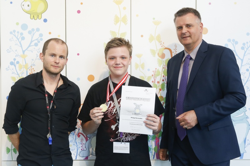 v.re.: Dienstleiter für Öffentlichkeitsarbeit Rudolf Gollia, Schüler Phillip Reinstadler und Lehrer Philipp Brunner bei der Urkunden- und Medaillenübergabe