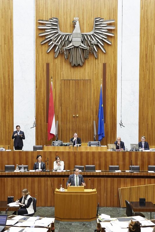 Nationalratsabgeordneter August Wöginger (V) am Rednerpult. Im Hintergrund auf der Regierungsbank Unterrichtsministerin Gabriele Heinisch-Hosek (S) und Familienministerin Sophie Karmasin (V). Am Präsidium Zweiter Nationalratspräsident Karlheinz Kopf (V).