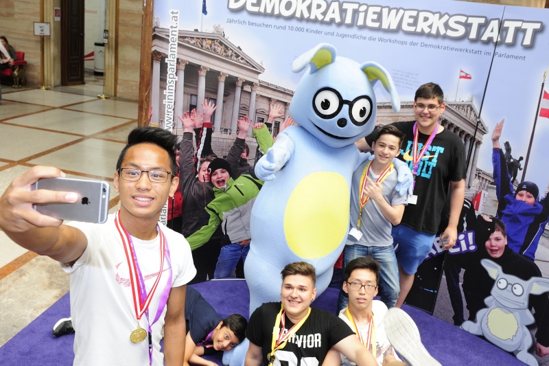 SchülerInnen mit dem Maskottchen Lesco vor dem Demokratiewerkstattplakat