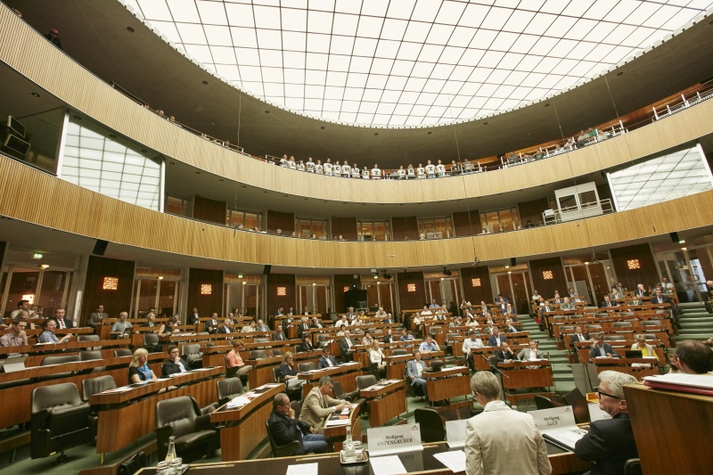 Blick Richtung EnqueteteilnehmerInnen. Auf der Besuchergalerie Jugendliche mit der Botschaft 'Klimaschutz jetzt' auf den T-Shirts