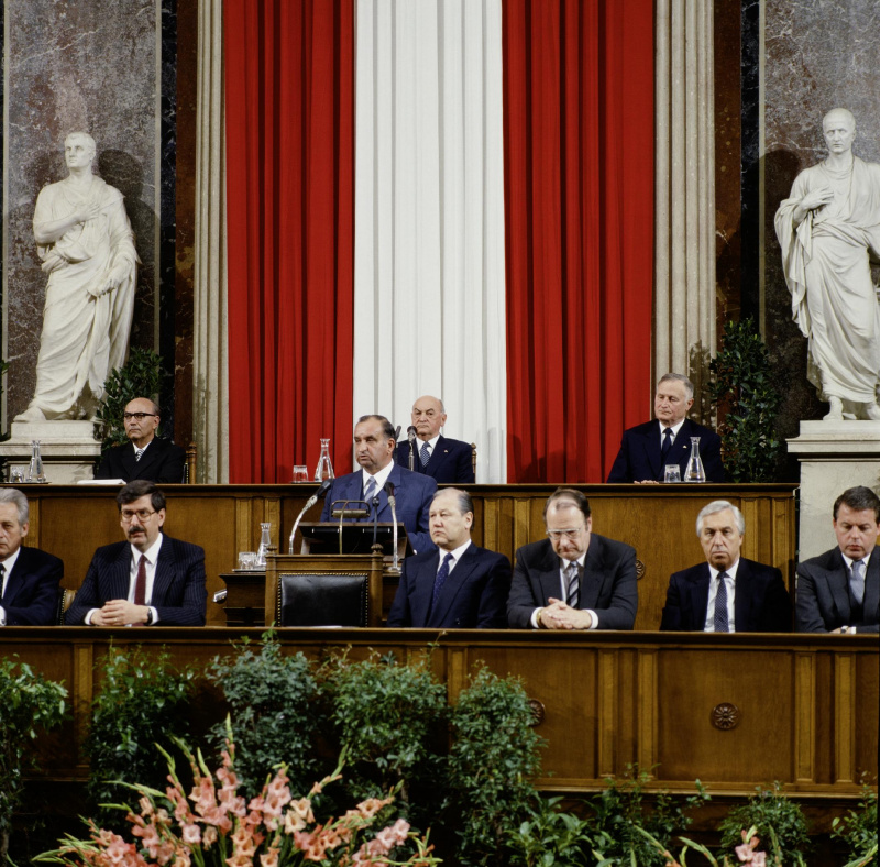 Blick Richtung Präsidium und Regierungsbank während der Ansprache von Bundeskanzler Fred Sinowatz (S) (am Rednerpult).

Am Präsidium von links.: Bundesratspräsident Eduard Pumpernig (V), Nationalratspräsident Anton Benya (S), Zweiter Nationalratspräsident Roland Minkowitsch (V).

Auf der Regierungsbank von links: Außenminister Leopold Gratz (S), Handelsminister und Vizekanzler Norbert Steger (F), Innenminister Karl Blecha (S), Justizminister Harald Ofner (F), Sozialminister Alfred Dallinger(S), Finanzminister Franz Vranitzky (S).