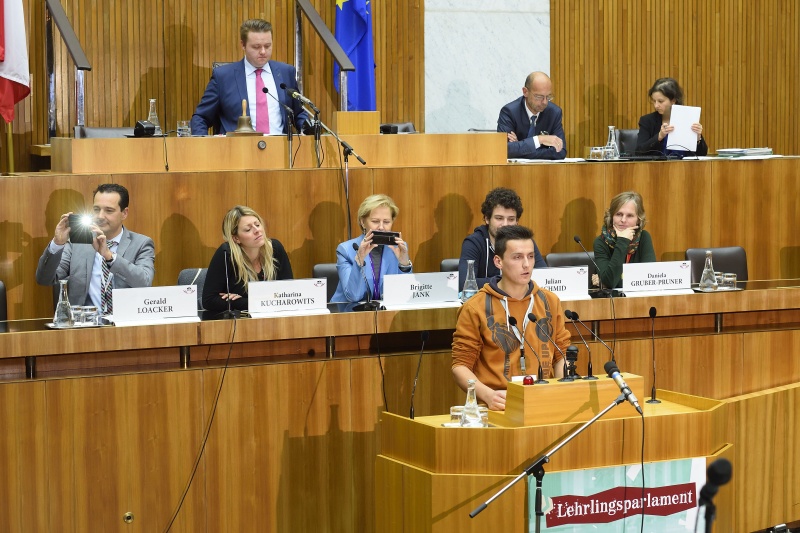 Rede eines Lehrlings im Plenarsaal des Nationalrates. Auf der Regierungsbank von links: Nationalratsabgeordneter Gerald Loacker (N), Nationalratsabgeordnete Katharina Kucharowits (S), Nationalratsabgeordnete Brigitte Jank (V), Nationalratsabgeordneter Julian Schmid (G), Bundesrätin Daniela Gruber-Pruner (S). Am Präsidium Bundesratspräsident Mario Lindner (S)