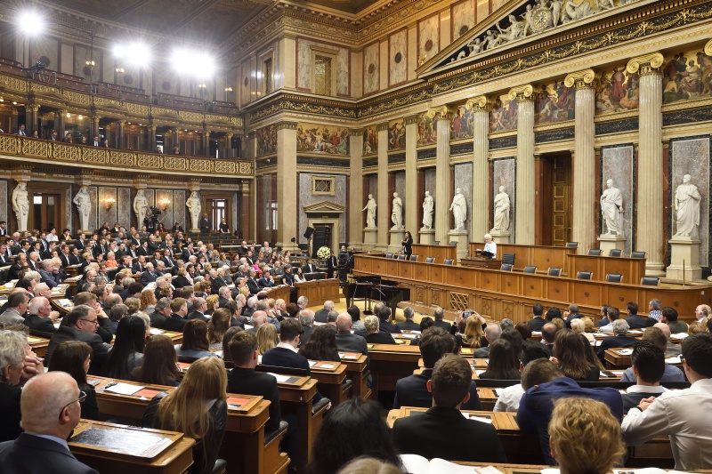 Gedenkrede der Historikerin und Holocaustüberlebenden Gertrude Schneider am Rednerpult. Blick Richtung VeranstaltungsteilnehmerInnen