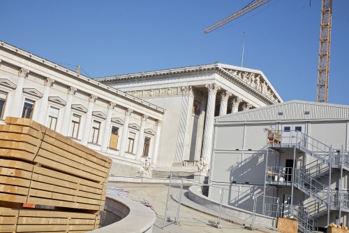 Parlamentsgebäude mit Baucontainer und Bauholz